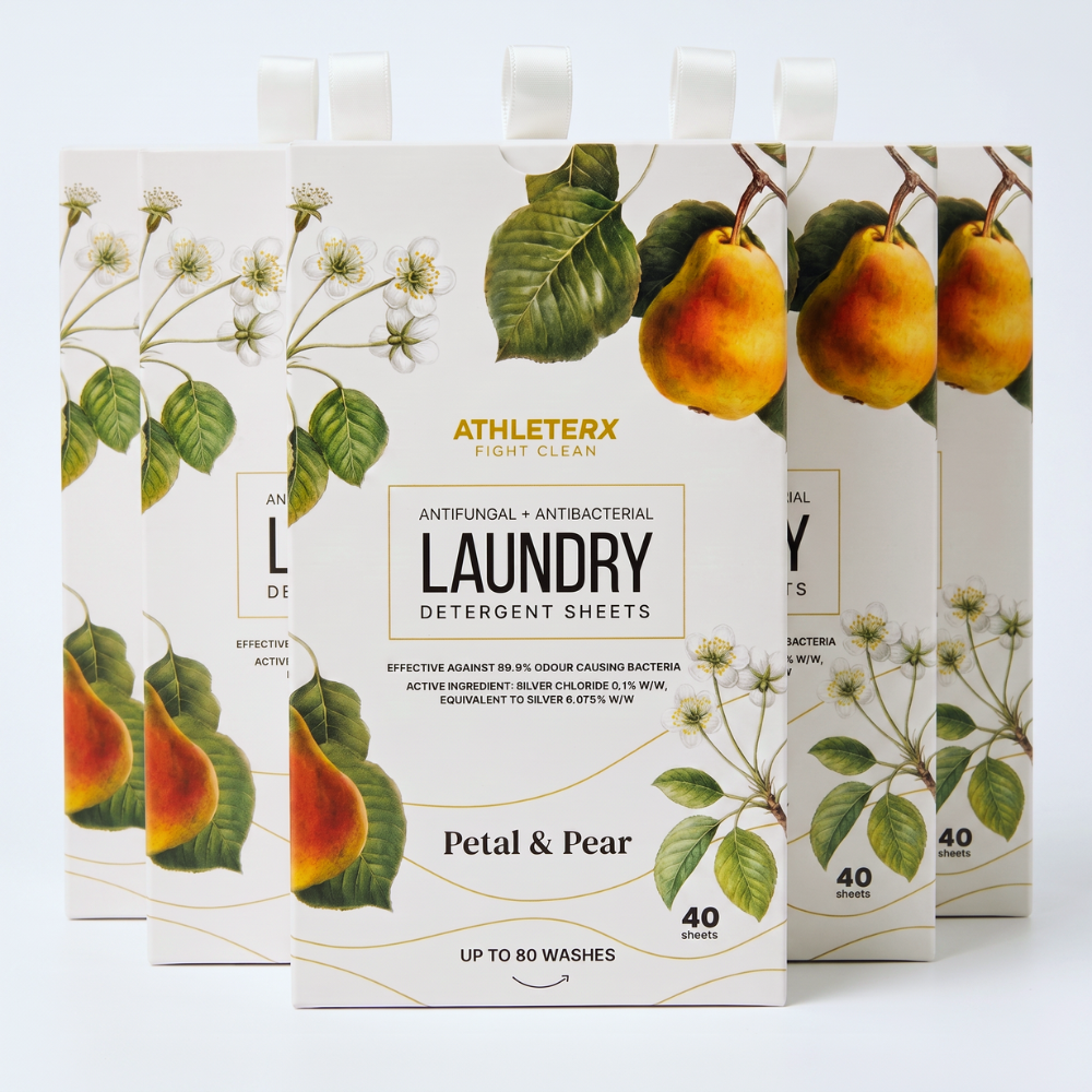Four Athlerton Light Clean laundry detergent sheets packages in a Petal & Pear scent, arranged in a fan shape against a clean white background. The packaging features a warm cream base with detailed botanical illustrations of green leaves and white blossoms, alongside fresh pear graphics showing yellow and orange tones.